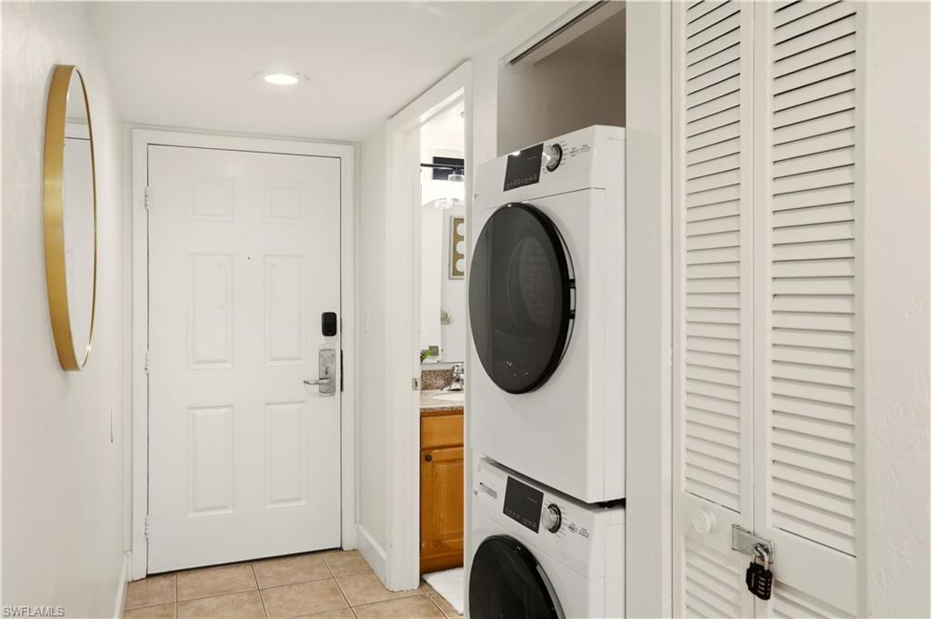 600 Neapolitan Way, Unit 254 Naples, FL 34103 - Photo 27 of 42 Laundry area featuring light tile patterned flooring, stacked washer / dryer, and recessed lighting