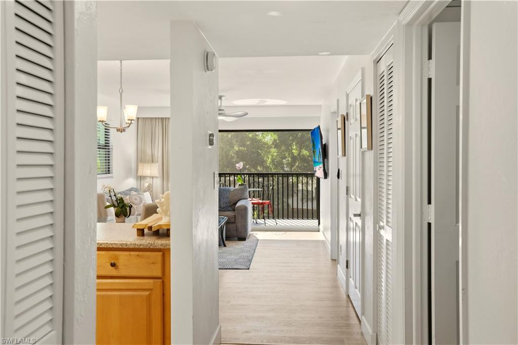 600 Neapolitan Way, Unit 254 Naples, FL 34103 - Photo 8 of 42 Hallway featuring light wood-style flooring, plenty of natural light, and hanging lights