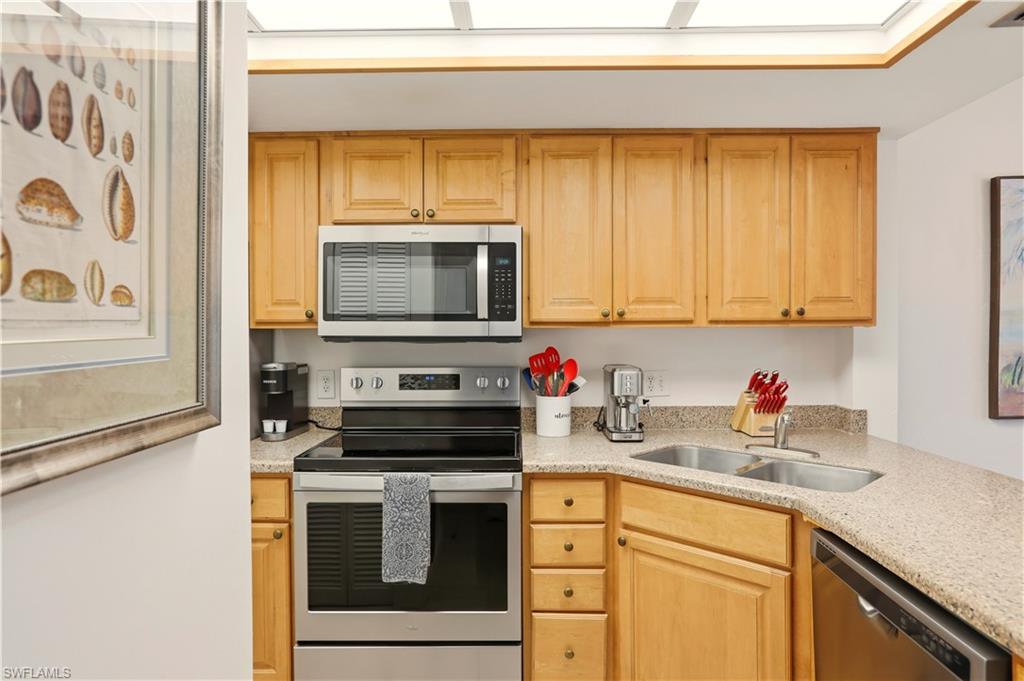 600 Neapolitan Way, Unit 254 Naples, FL 34103 - Photo 9 of 42 Kitchen featuring stainless steel appliances, light stone counters, and light wood finish cabinetry