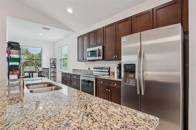 a kitchen with granite countertop a refrigerator and a sink