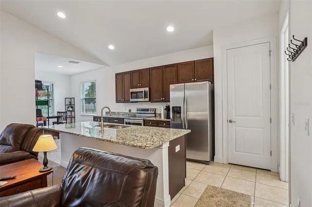 a kitchen with stainless steel appliances granite countertop a refrigerator a stove a sink a washer and dryer with wooden floor