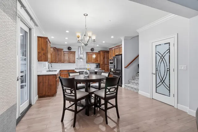 a view of a dining room and livingroom with furniture wooden floor a rug a painting and a chandelier