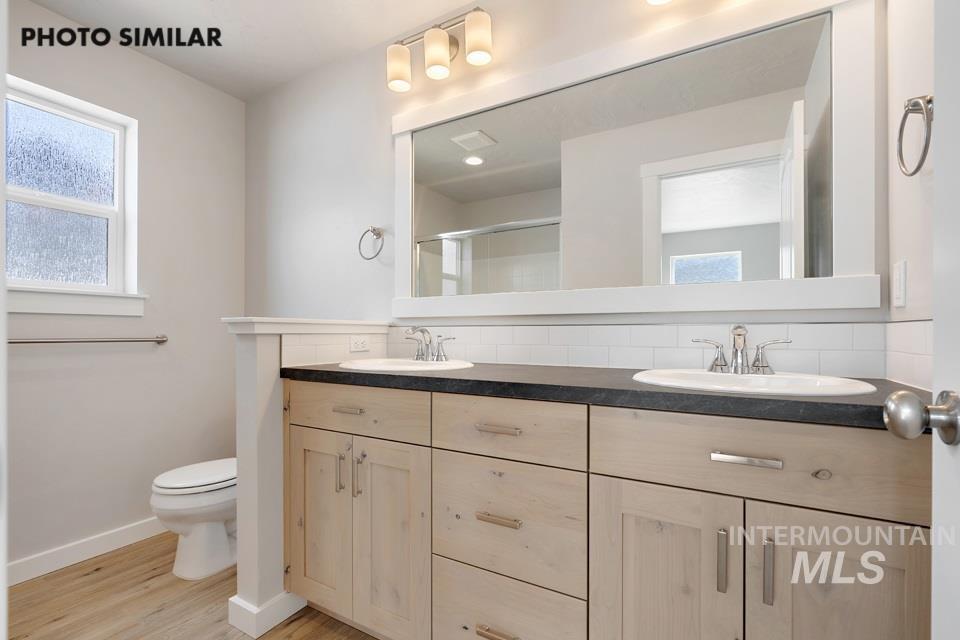 1676 Haystack Road Emmett, ID 83617 - Photo 15 of 32 Dual vanity with light wood-finish cabinetry, dark countertop, and undermount sinks