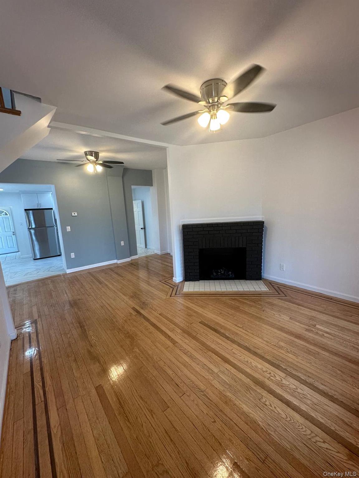 218-17 109th Avenue Queens, NY 11429 - Photo 2 of 35 Unfurnished living room featuring a brick fireplace, wood-type flooring, and ceiling fan