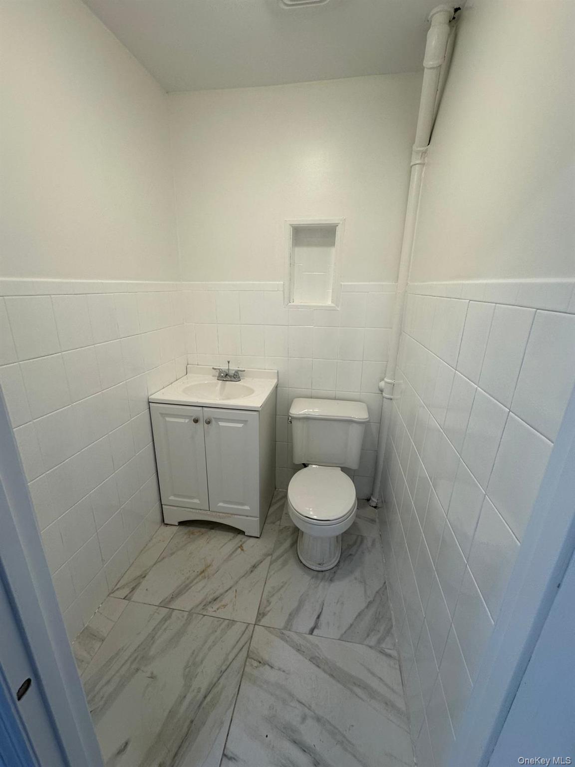 218-17 109th Avenue Queens, NY 11429 - Photo 30 of 35 Bathroom featuring tile walls, vanity, wainscoting, and light marble finish floors