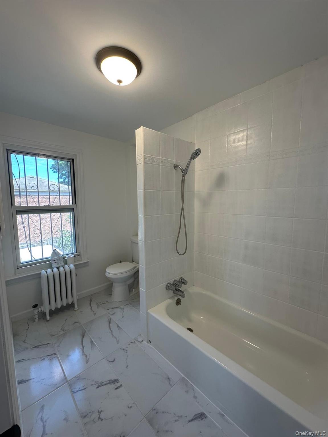 218-17 109th Avenue Queens, NY 11429 - Photo 34 of 35 Bathroom with washtub / shower combination, radiator heating unit, and light marble finish flooring