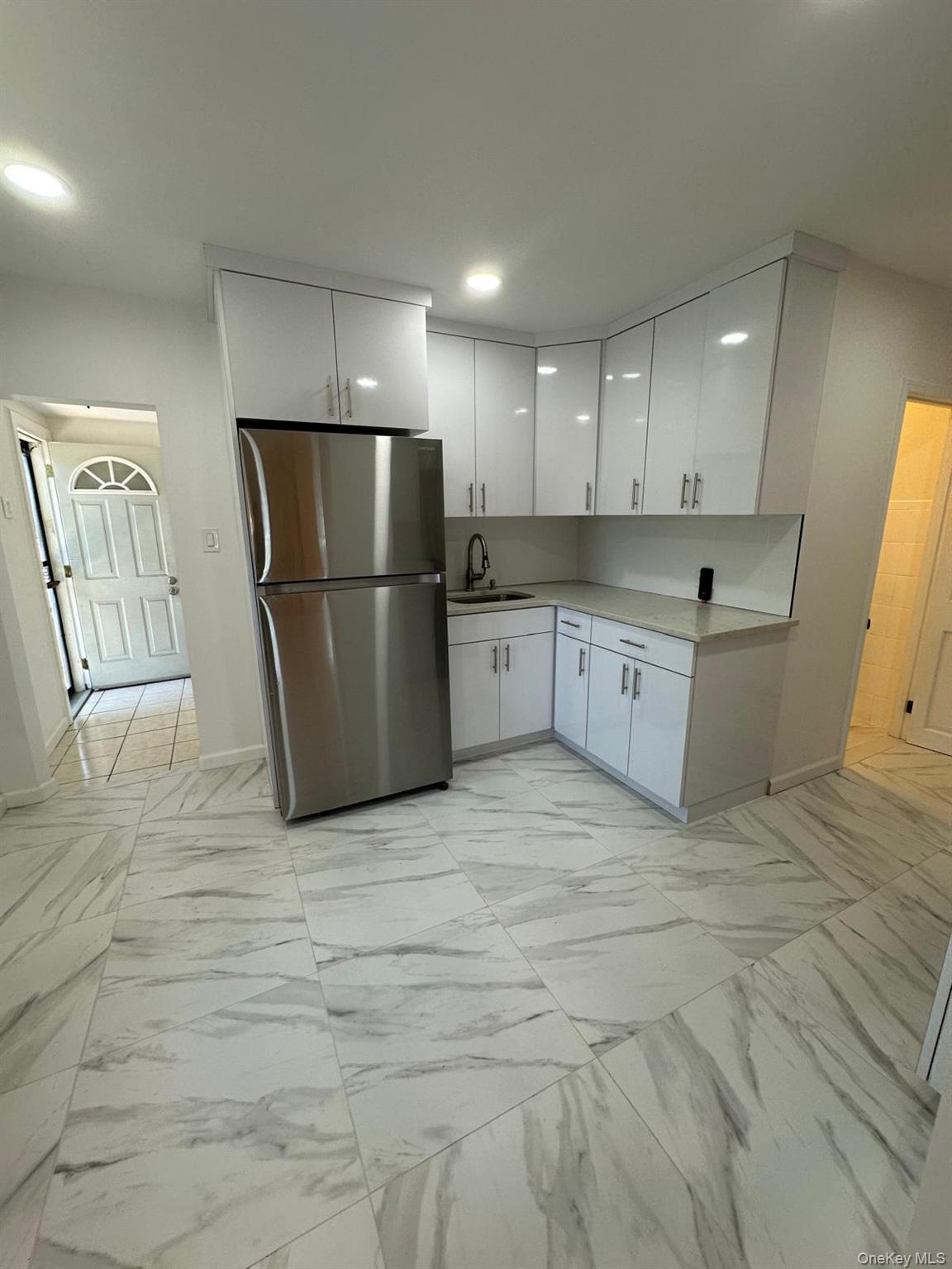 218-17 109th Avenue Queens, NY 11429 - Photo 10 of 35 Kitchen featuring white cabinetry, freestanding refrigerator, light marble finish flooring, and recessed lighting
