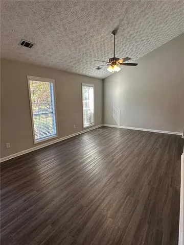 an empty room with wooden floor chandelier and windows