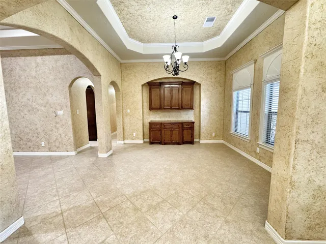 a view of a hallway with entryway windows chandelier and a kitchen view