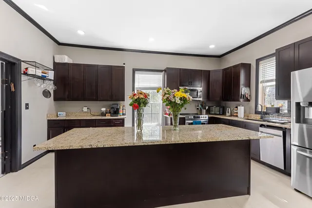 a kitchen with kitchen island granite countertop a sink stove and refrigerator