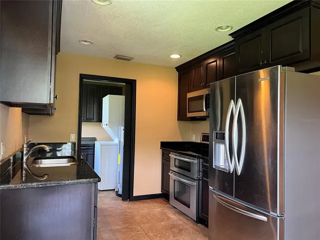 a kitchen with stainless steel appliances granite countertop a refrigerator and a sink