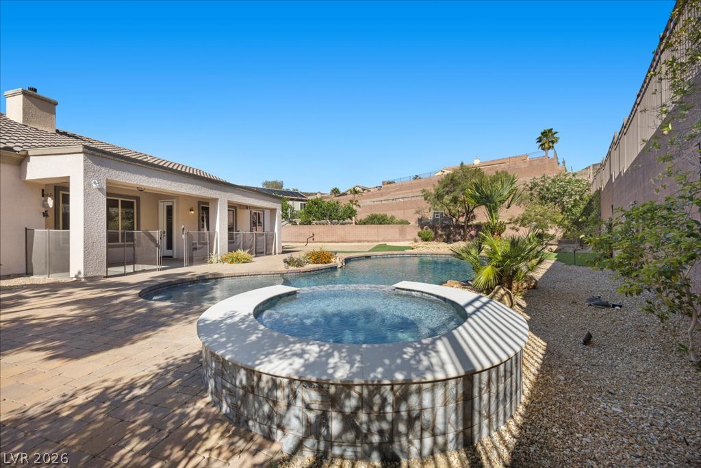 2125 De Rouge Avenue Henderson, NV 89044 - Photo 77 of 96 A private backyard oasis features a shimmering pool and an integrated spa, all set on a spacious paver patio.
