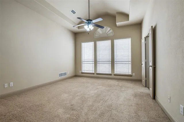 an empty room with chandelier fan and windows