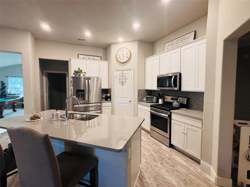 6820 Elm Street Rowlett, TX 75089 - Photo 3 of 12 a kitchen with stainless steel appliances granite countertop a sink a stove a refrigerator cabinets and chairs