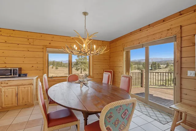 a view of a dining room with furniture a chandelier and large windows