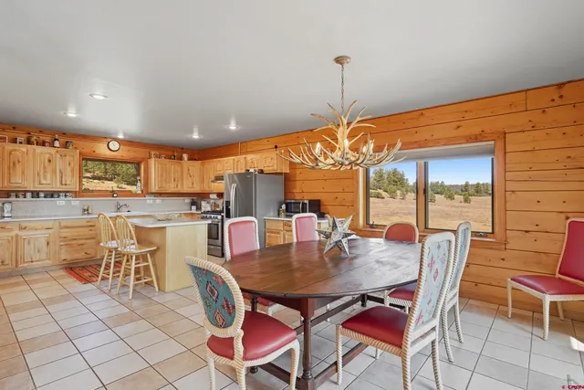 a dining area with stainless steel appliances a dining table chairs and a rug