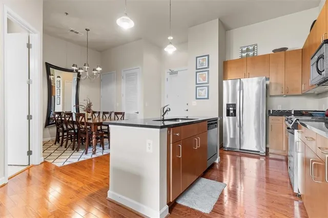 a kitchen with stainless steel appliances granite countertop a refrigerator a sink a stove and a wooden floors