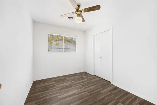 an empty room with a window and a ceiling fan