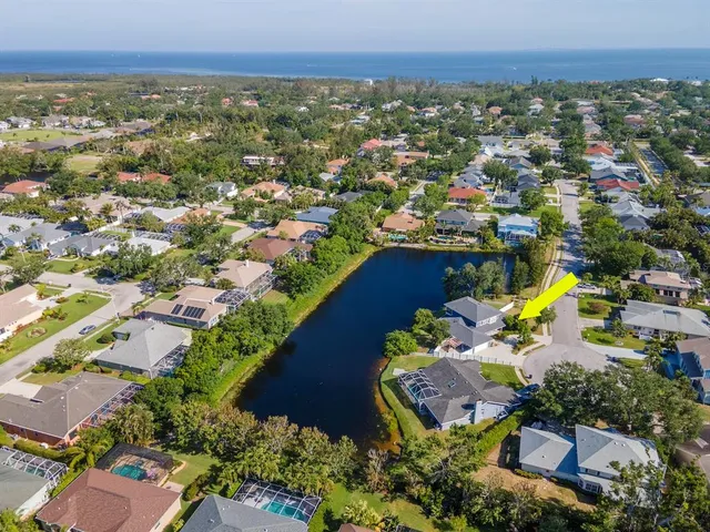 an aerial view of ocean and residential houses with outdoor space