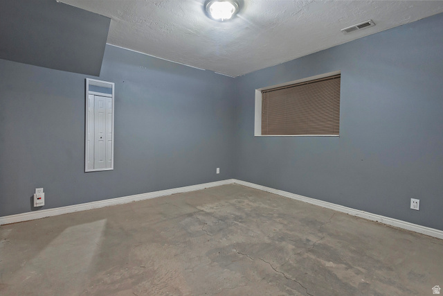 3310 Creek Road Salt Lake City, UT 84121 - Photo 32 of 49 Room featuring textured blue-gray walls, white trim, and a concrete floor