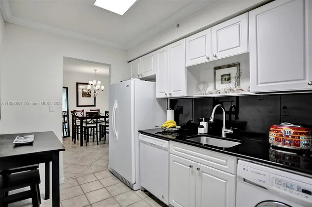 a kitchen with granite countertop a refrigerator a stove a dining table and chairs