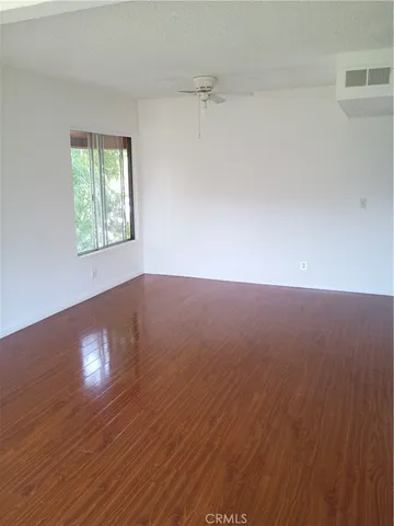 a view of an empty room with wooden floor and a window