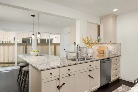 a kitchen with granite countertop white cabinets and stainless steel appliances