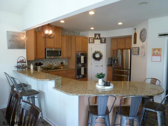 218 Surf Road Egg Harbor Township, NJ 08234 - Photo 7 of 28 a kitchen with stainless steel appliances kitchen island granite countertop a dining table chairs and refrigerator