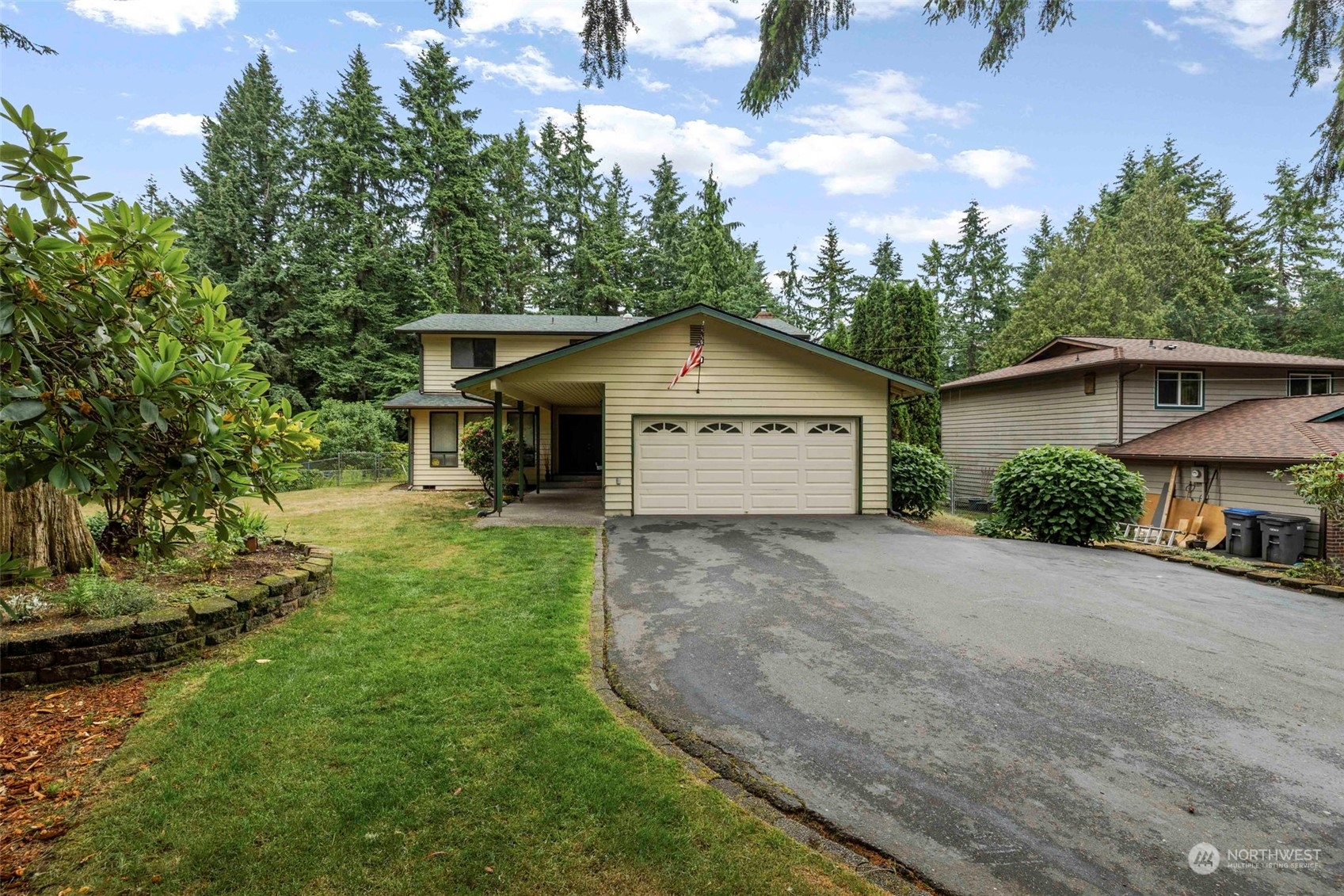 a view of a house with a yard plants and large tree