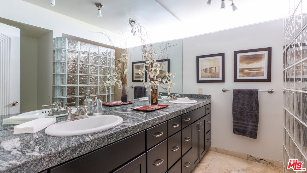 70375 Calico Road Rancho Mirage, CA 92270 - Photo 24 of 46 a bathroom with a granite countertop sink a large mirror and a shower