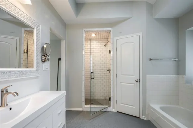 a bathroom with a tub shower sink and mirror