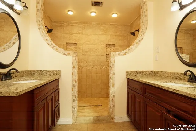 a bathroom with a granite countertop sink a mirror and shower