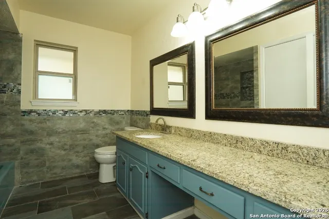 a bathroom with a granite countertop sink and a mirror