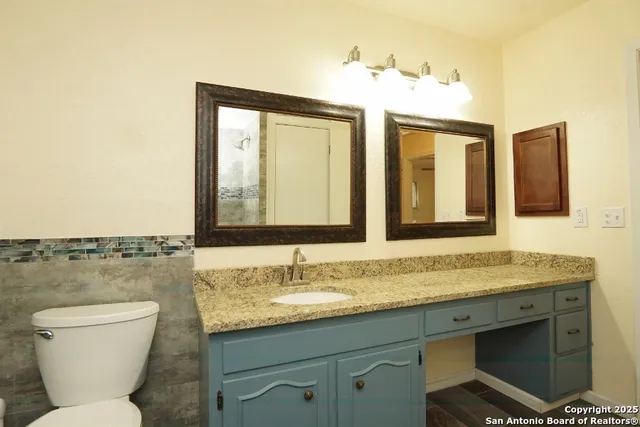 a bathroom with a granite countertop toilet sink and mirror