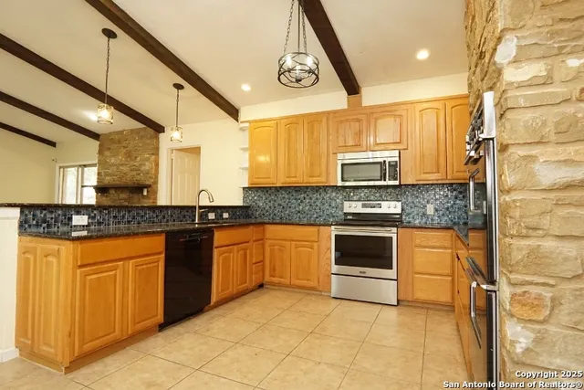 a kitchen with stainless steel appliances granite countertop a stove a sink and a microwave