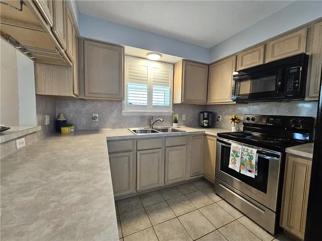 a kitchen with stainless steel appliances granite countertop a stove a sink and a microwave