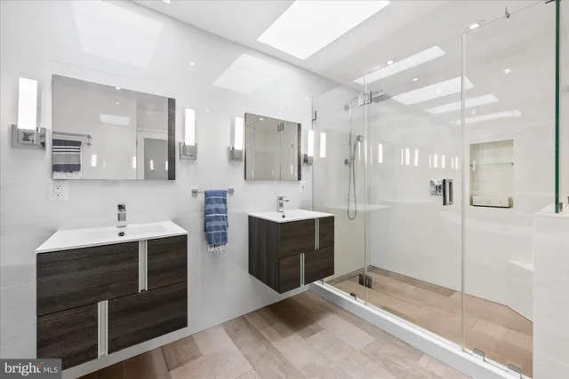 a spacious bathroom with a double vanity sink a mirror a bathtub and next to a window