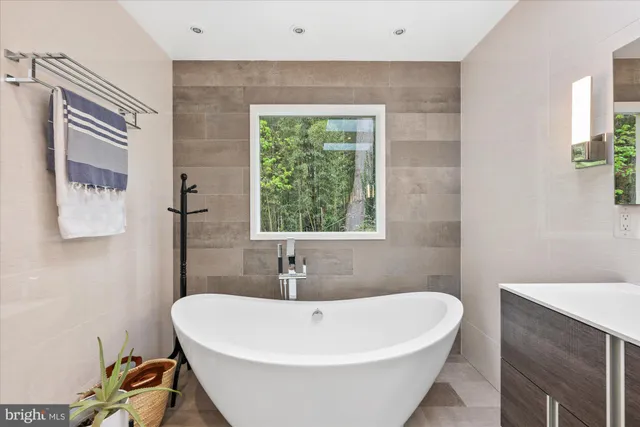 a spacious bedroom with a bed a mirror and a large window with wooden floor