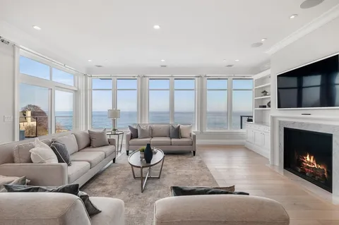 a living room with furniture a fireplace and a large window with balcony view