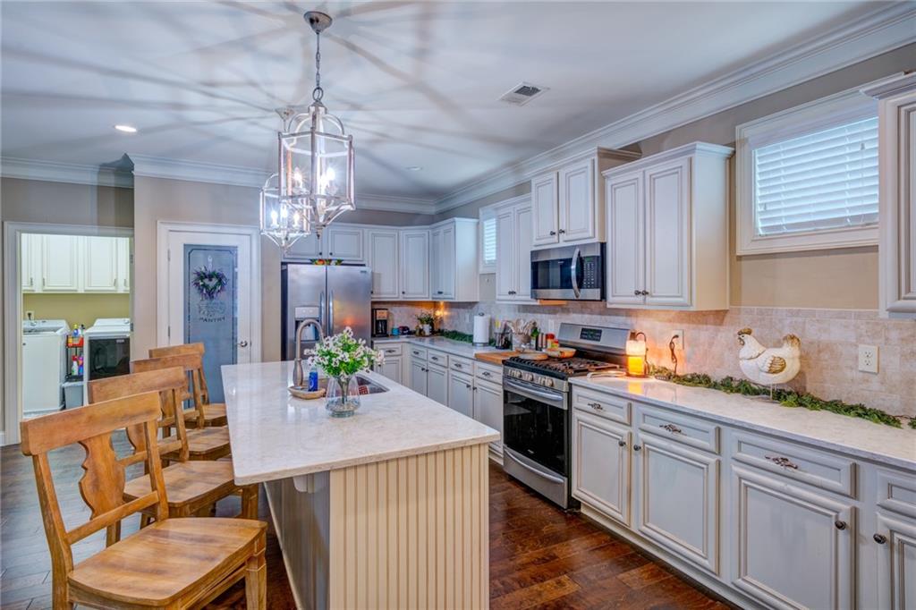 2443 Barrett Preserve Court Marietta, GA 30064 - Photo 4 of 46 a kitchen with stainless steel appliances granite countertop a sink dishwasher a stove a refrigerator with a dining table and chairs