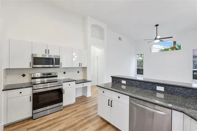 a kitchen with granite countertop stainless steel appliances a stove cabinets and wooden floor