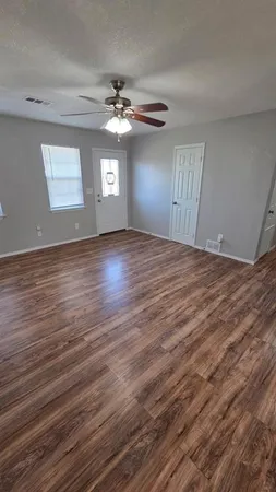 a view of an empty room with window and wooden floor