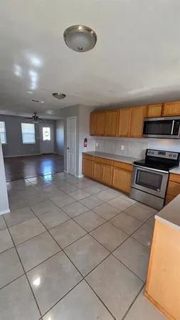 a living room with stainless steel appliances kitchen island granite countertop a rug and a view of kitchen