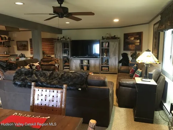 a living room with couches a flat screen tv and kitchen view
