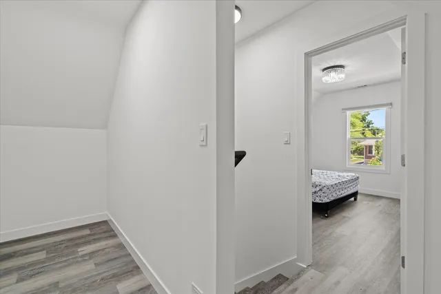a view of a hallway with wooden floor and a bedroom
