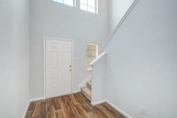 a view of an empty room with wooden floor and stairs