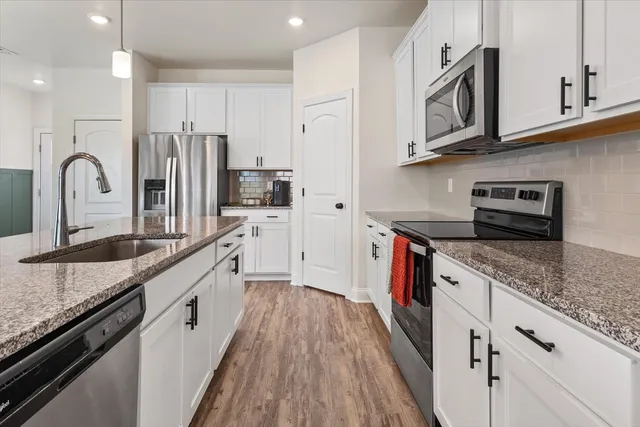 a large kitchen with stainless steel appliances granite countertop a lot of counter space and wooden floors