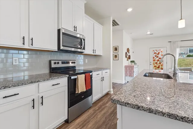 a kitchen with stainless steel appliances granite countertop a stove a sink and a microwave