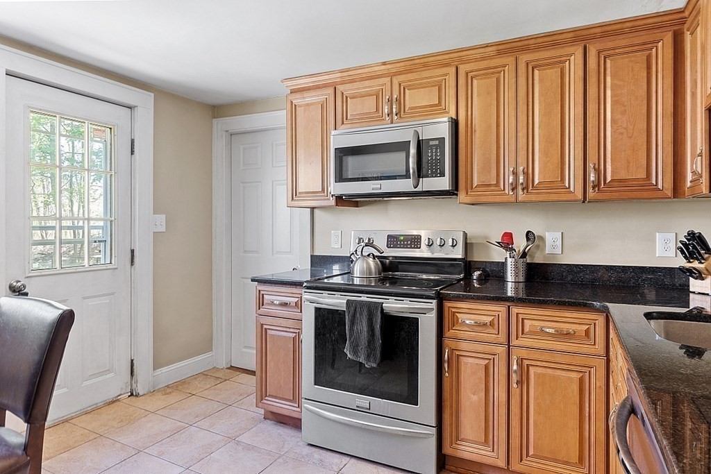 a kitchen with stainless steel appliances granite countertop a stove a microwave and a white cabinets