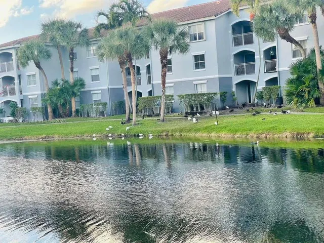 a view of a lake with a big yard and large trees